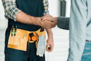 Handshake Between Client And Contractor Wearing Tool Belt